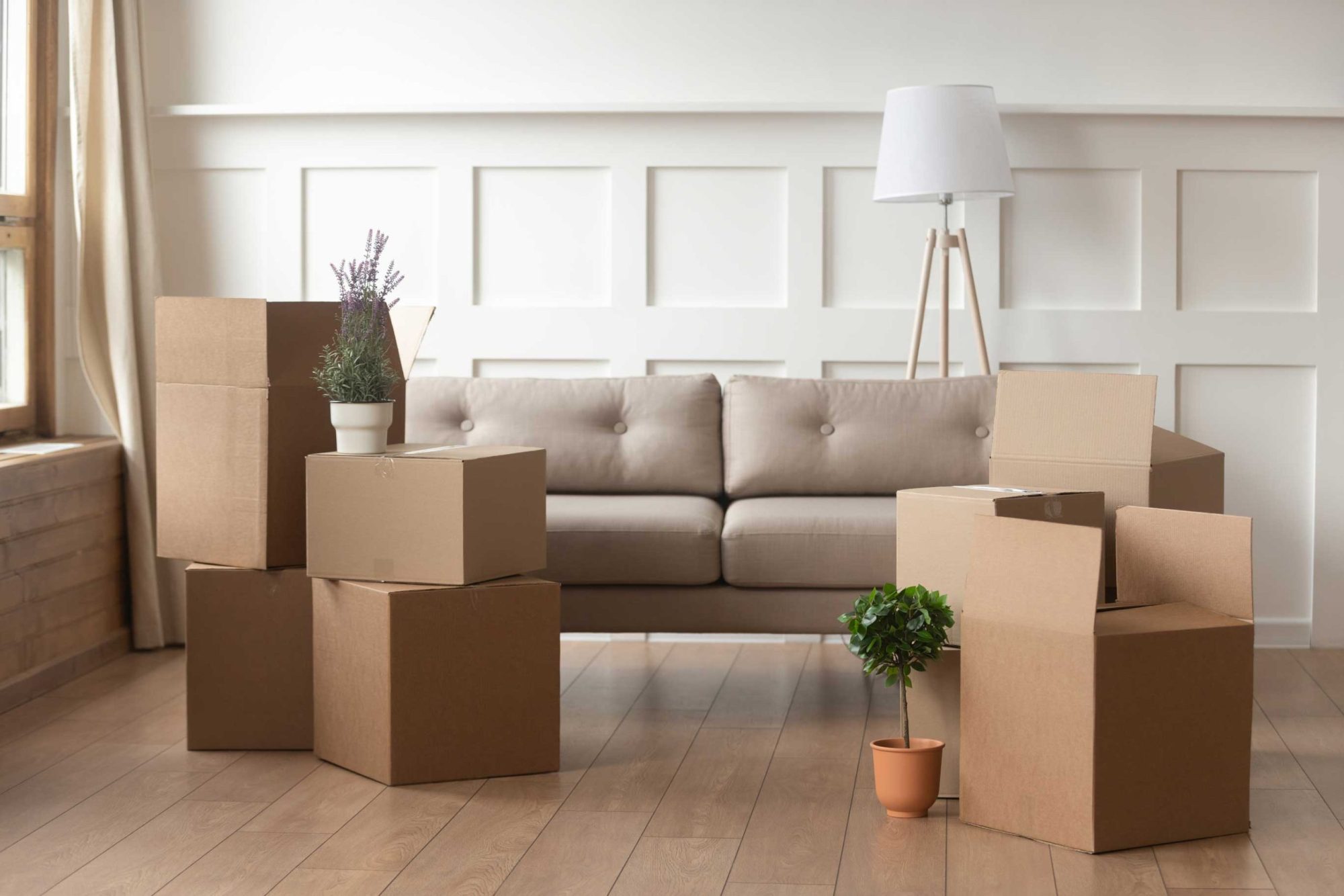 Moving day concept, cardboard boxes in modern house living room. Moving day concept, cardboard carton boxes stack with household belongings in modern house living room, packed containers on floor in new home, relocation, renovation, removals and delivery service